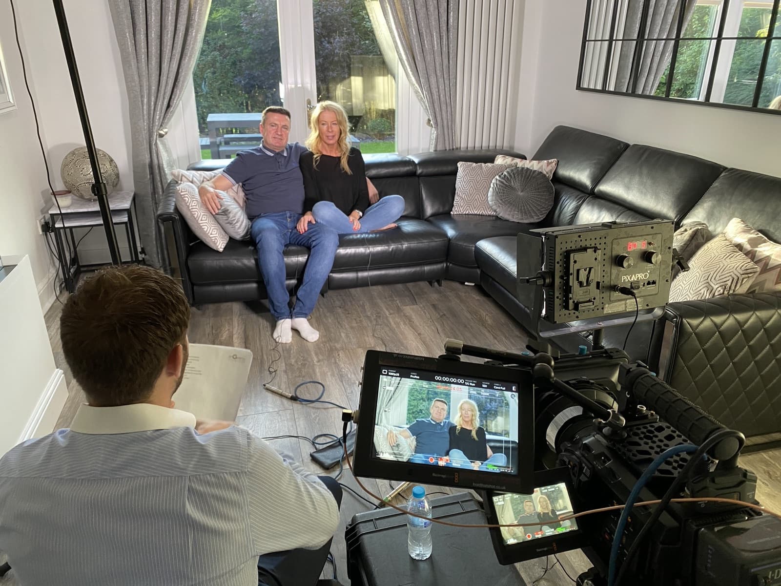 Our crew filming an interview with two people on a sofa in their living room